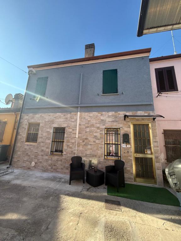 a brick building with two chairs in front of it at Il nido delle rondini in Comacchio