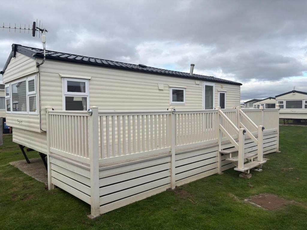 a white tiny house with a white fence at TheLeoHome in Selsey