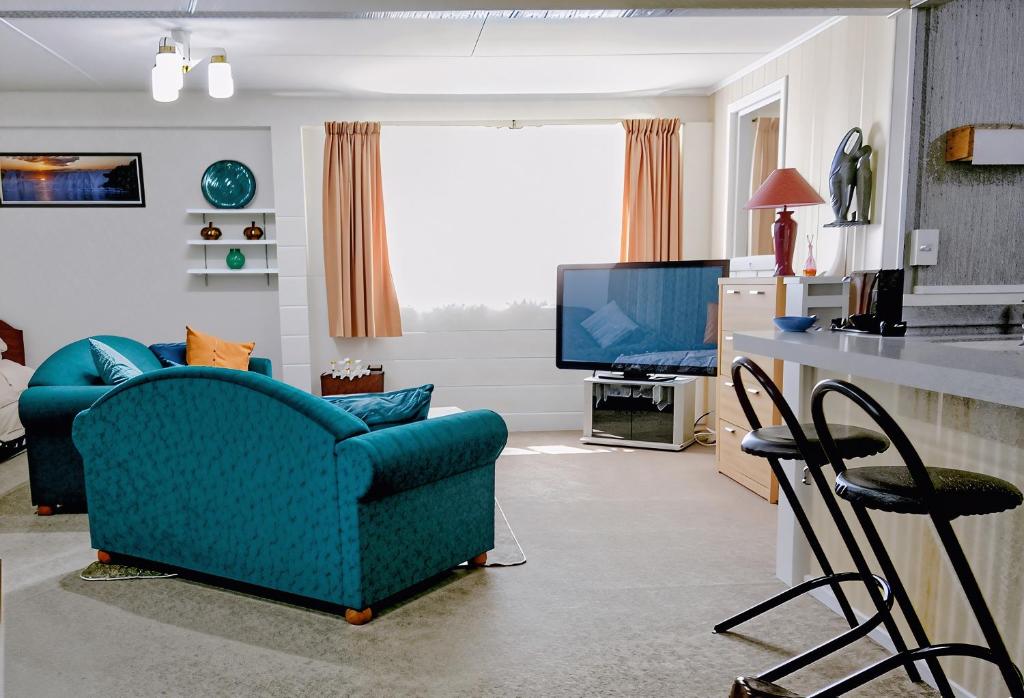 a living room with a blue couch and a television at Park View 'Home Away From Home' in Feilding