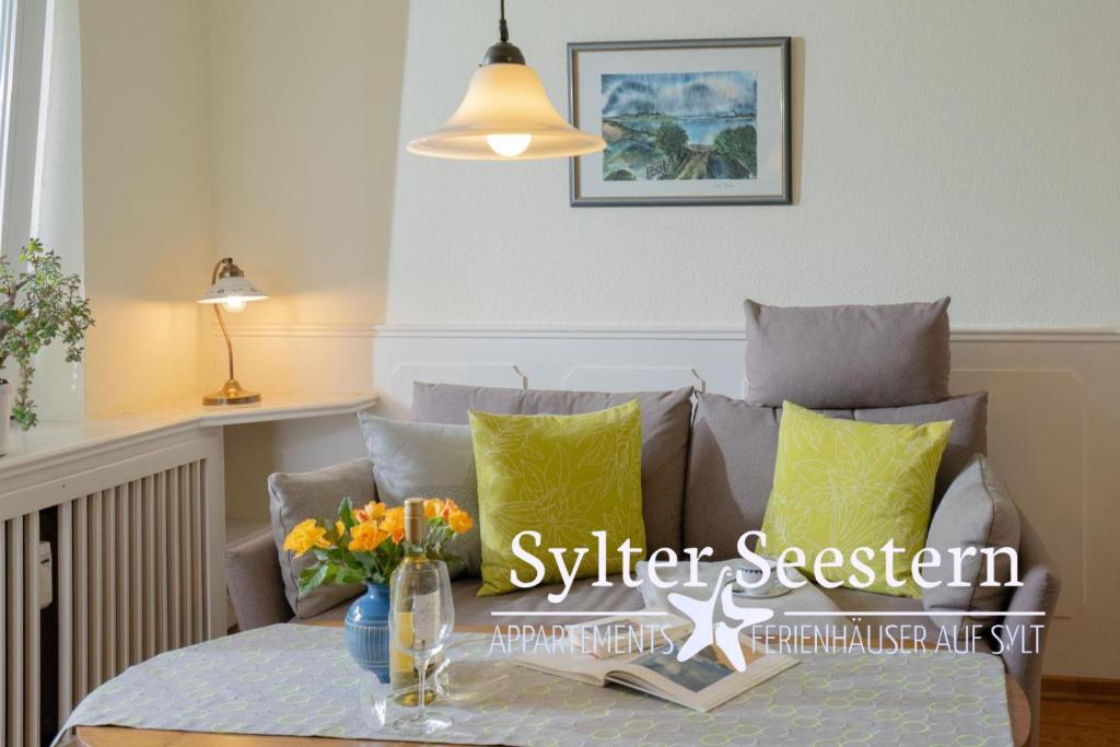 un salon avec un canapé et une table avec des fleurs dans l'établissement Sylter Seestern App Momme, à Morsum