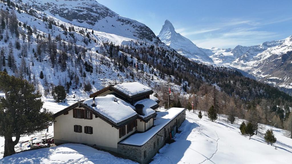 une maison dans la neige sur une montagne enneigée dans l'établissement Berghaus Grünsee, à Zermatt