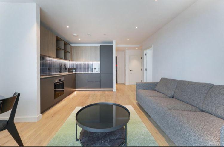 a living room with a couch and a table and a kitchen at Casa Mono One Bedroom Flat in Southall