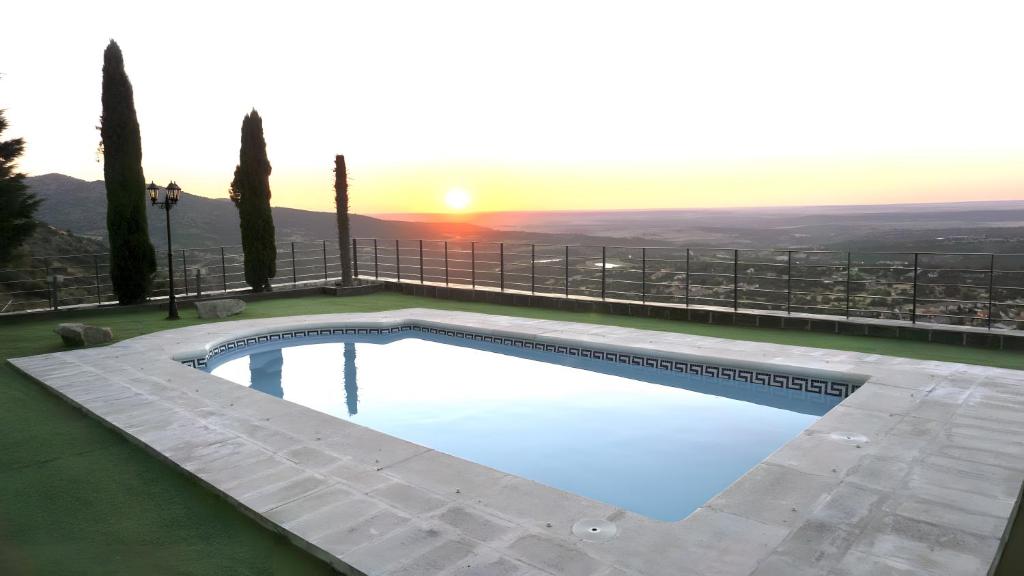 a swimming pool with the sunset in the background at Villa Los Ángeles - El Espinar in Los Ángeles de San Rafael
