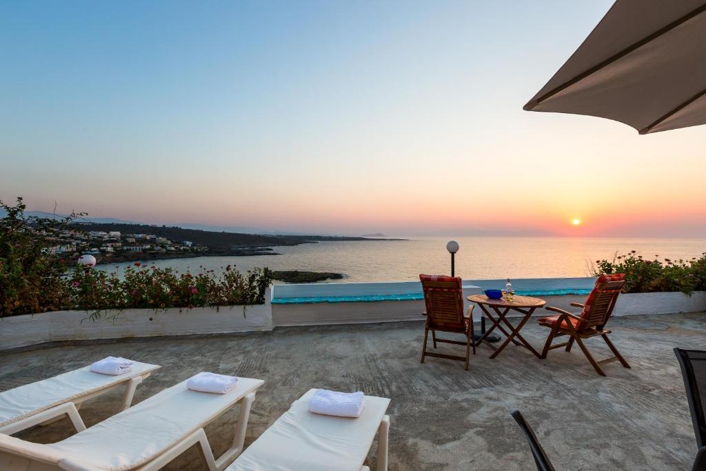 un patio con tavolo, sedie e vista sull'oceano di Kalathas Sunset Villa a Kalathas