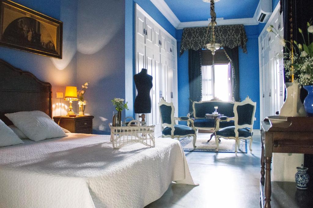 ヘレス・デ・ラ・フロンテーラにあるCasa Palacio Jerezanaの青いベッドルーム(ベッド1台、テーブル、椅子付)