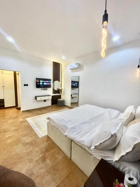 アブジャにあるND2 Luxury Apartment Jabiのベッドとテレビのある白い寝室