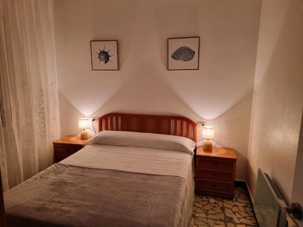 Un dormitorio con una cama con dos mesitas de noche y dos lámparas. en O Curro de Arou, en Arou