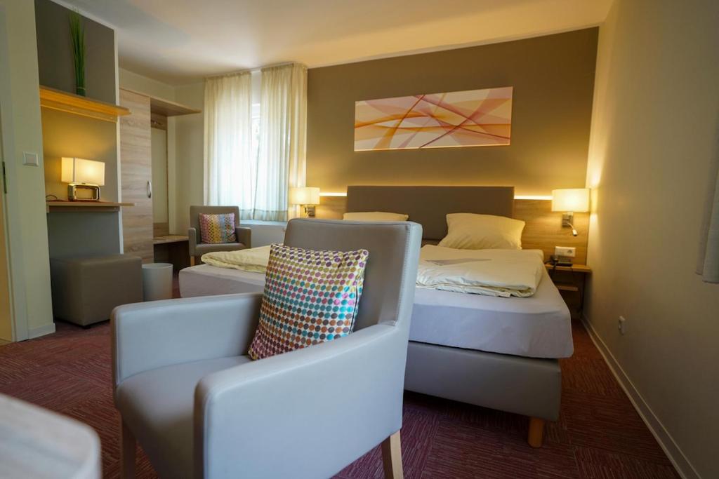 une chambre d'hôtel avec deux lits et une chaise dans l'établissement Altdeutscher Hof Beckord, à Gütersloh