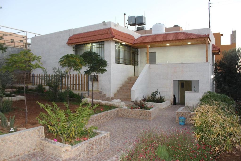 a large white house with a garden in front of it at Spacious Villa near Ma'in Hot Springs & Mount Nebo in Umm Juraysāt