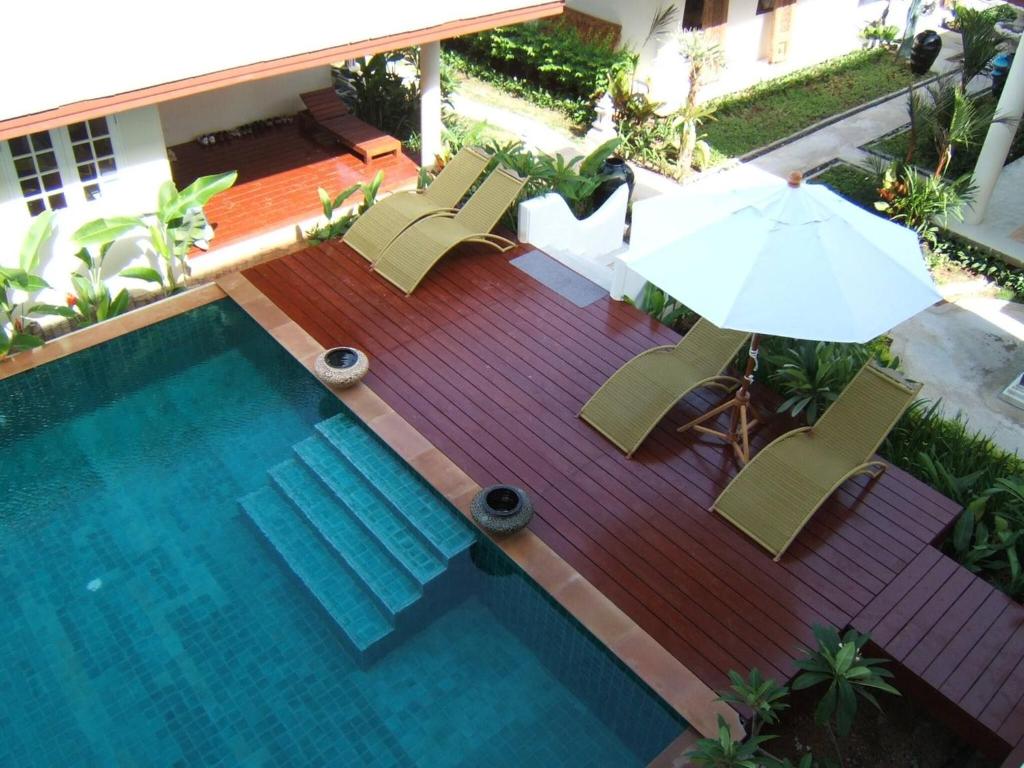 two chairs and an umbrella next to a swimming pool at Nakara Samui-Deluxe beach front in Ban Thong Phlu