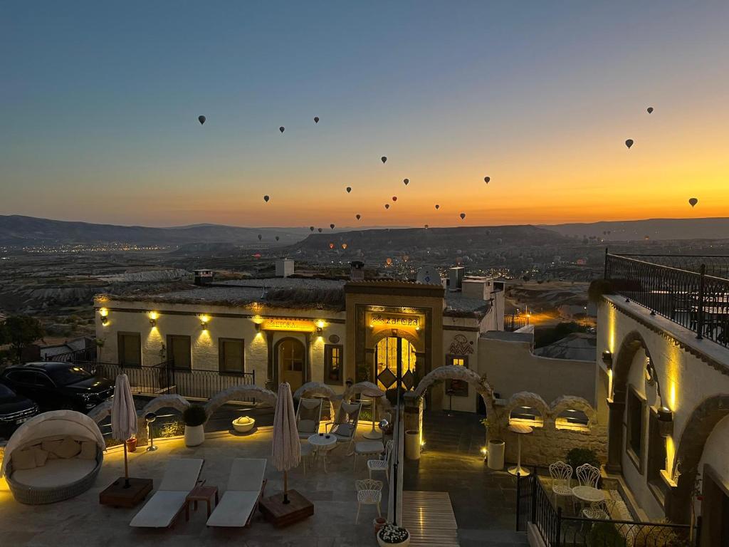 ウチヒサールにあるZafora Cave Suites Hotel Cappadociaの夕暮れ時のテーブルとパラソルのある建物の眺め