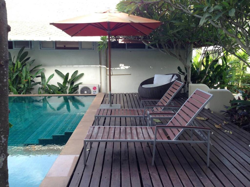 a pair of chairs and an umbrella next to a swimming pool at Nakara Samui S2 One Bedroom Apt in Ban Thong Phlu