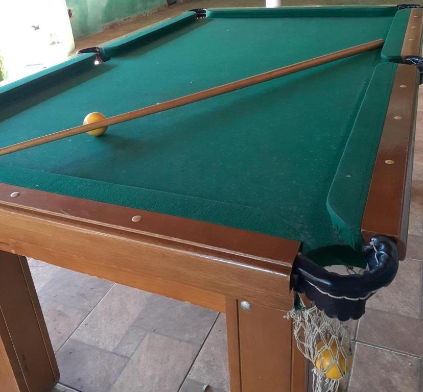 a green pool table with two cue sticks and a ball at Chácara in Franco da Rocha