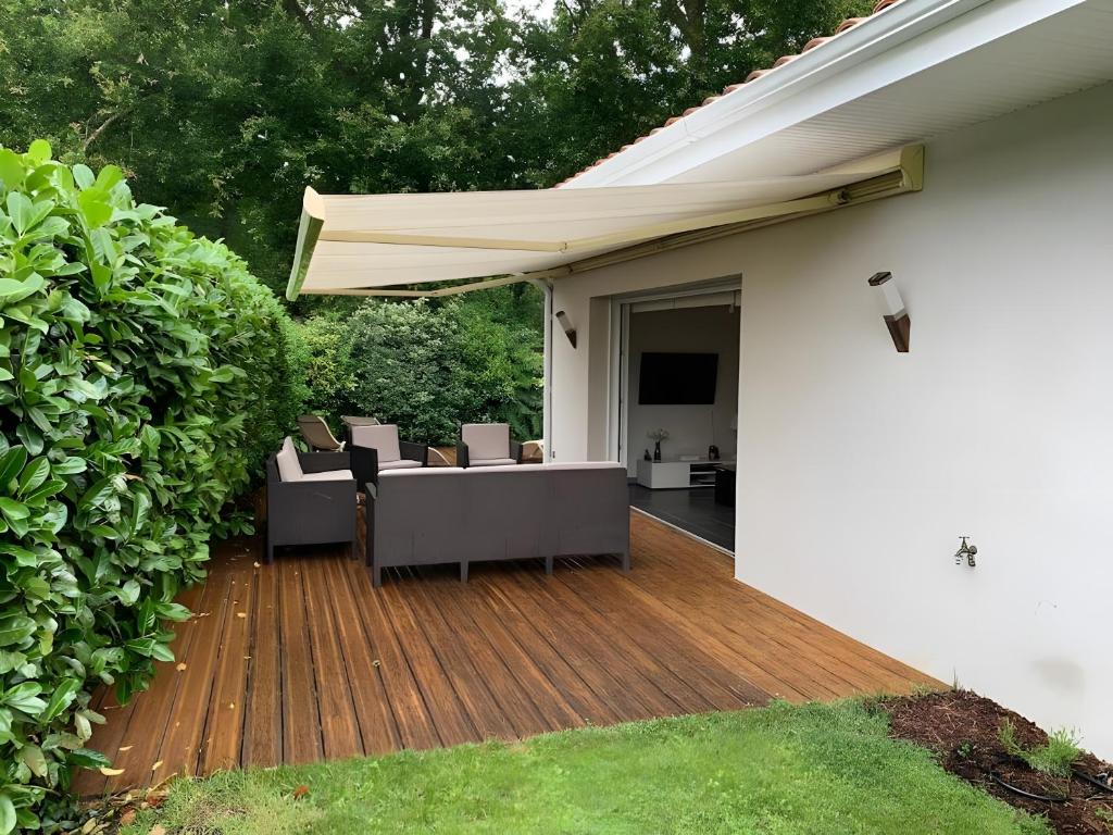 a deck with chairs and an umbrella on a house at Villa jacuzzi entre Lac et Ocean in Cazaux