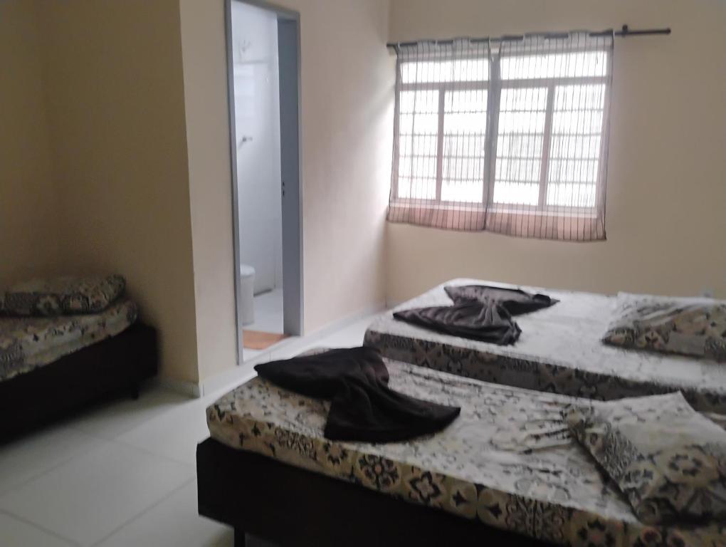 two twin beds in a room with a window at Apartamento com 3 quartos a só 200 metros da Basílica in Aparecida
