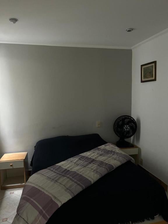 a bedroom with a bed and a white wall at Pitangueiras Condomínio Sobre as Ondas in Guarujá
