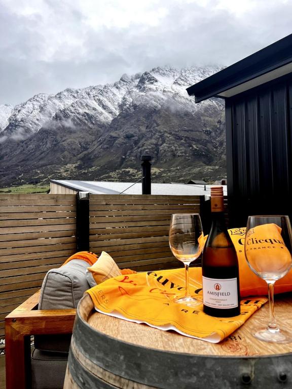 a bottle of wine and two glasses on a table at Queenstown Studio with Mountain Views in Frankton