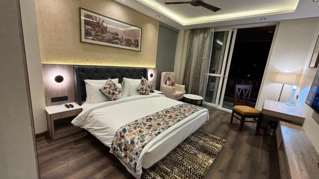 een slaapkamer met een groot wit bed en een raam bij Carom Hotel Manali in Manāli