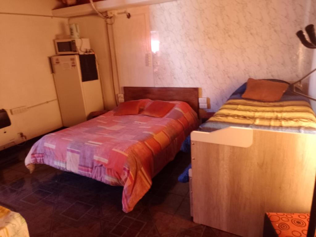 a bedroom with two beds and a refrigerator at Guiñazú in Mendoza