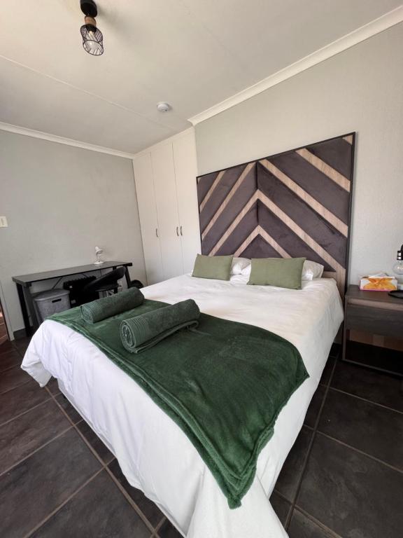 a bedroom with a large bed with green sheets at 15 On Palm East in Edenvale