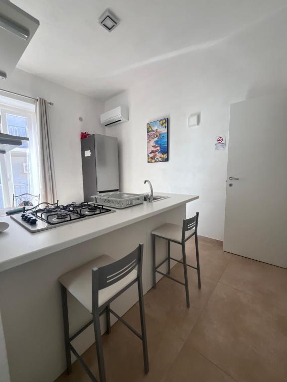 a kitchen with a counter with a stove and chairs at Kalsa’s House Noto in Noto