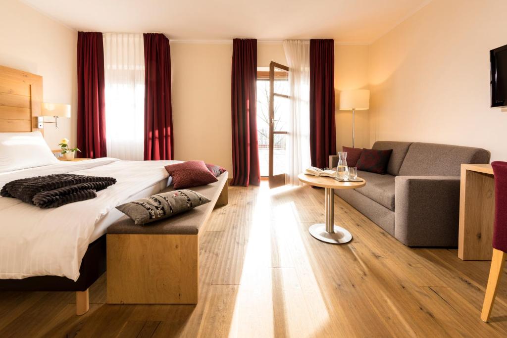 a hotel room with a bed and a couch at Euler Neuschönau - Naturhotel & Chalets in Neuschönau