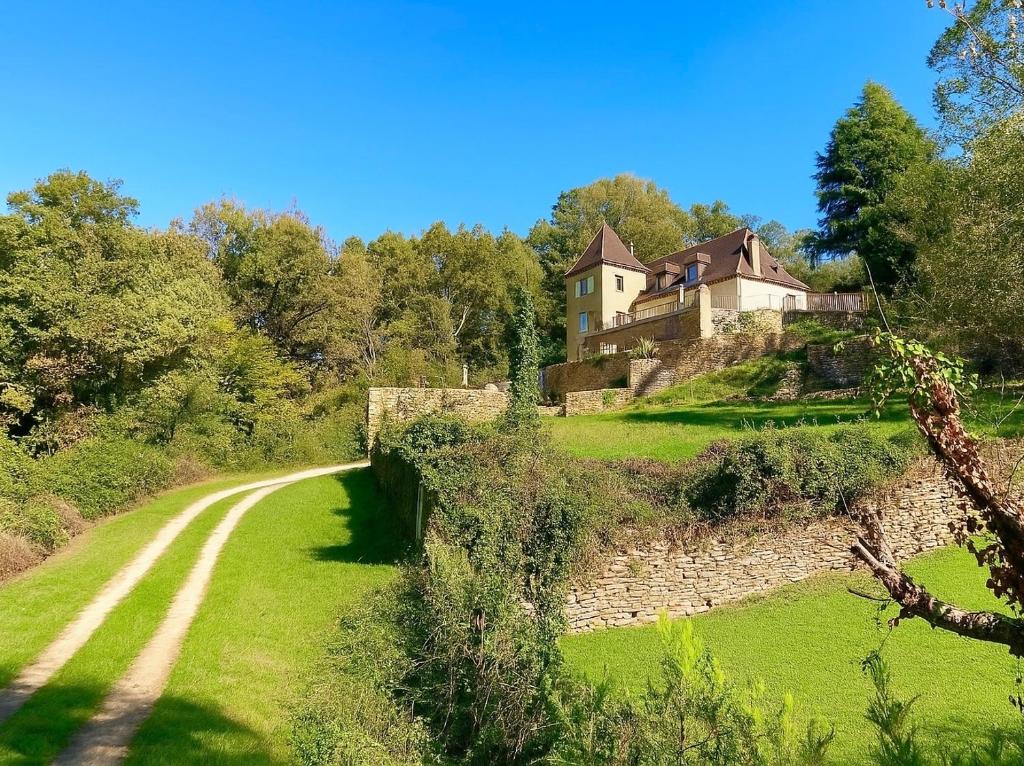 a house on top of a hill with a dirt road at Gîte Le Vélo Bleu - Airco & Parking in Sarlat-la-Canéda