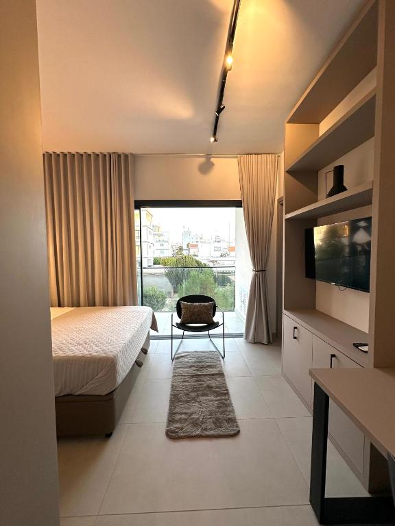 a bedroom with a bed and a television and a chair at Nesseus Lux Suites - Near Unic & EUC in Ayios Dhometios
