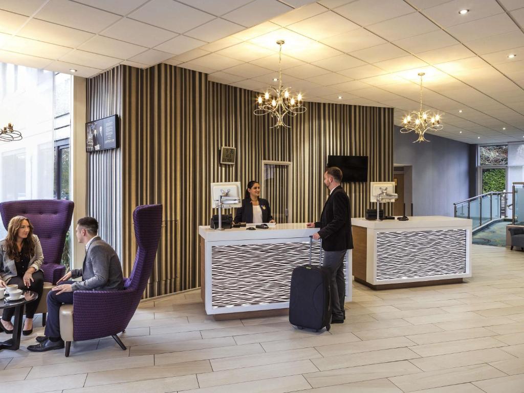 un homme debout à un comptoir dans un hall dans l'établissement Novotel Coventry, à Coventry