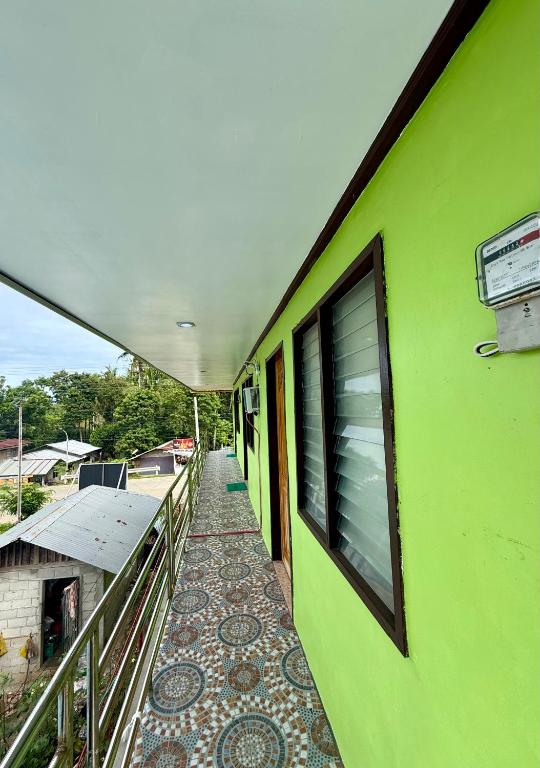 a green building with a walkway next to a balcony at JJL pension house in Siquijor