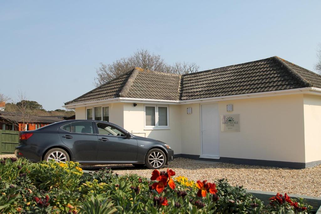 a black car parked in front of a house at Honeysuckle Cottage with Hot Tub Park Facilities in Milford on Sea