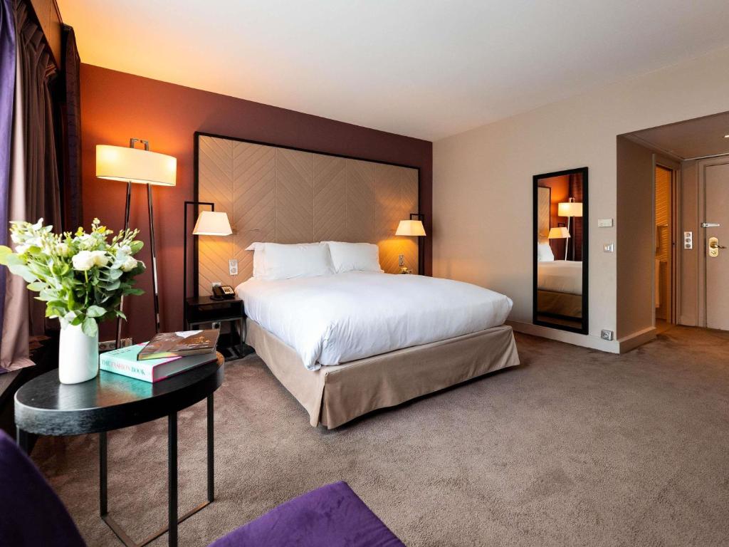 Una habitación de hotel con una cama grande y una mesa. en Sofitel Strasbourg Grande Ile, en Estrasburgo