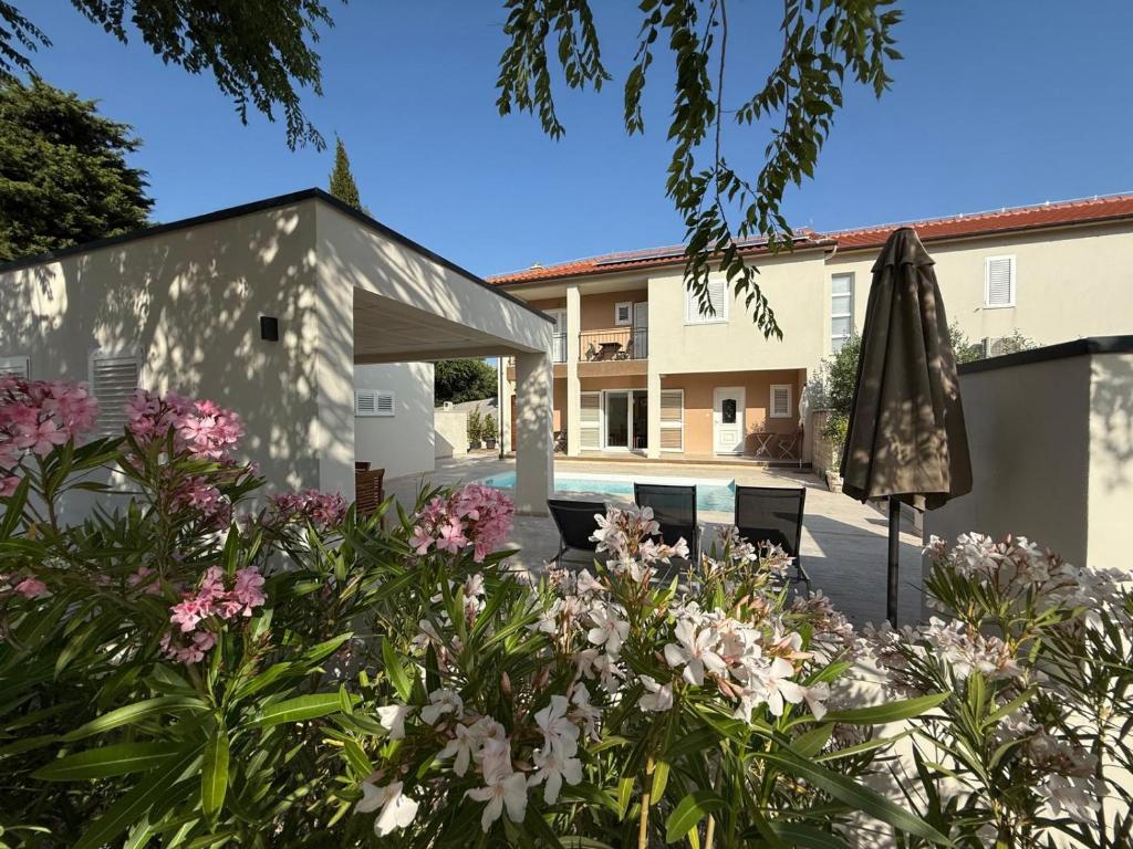 a garden with an umbrella and flowers in front of a house at Ferienhaus FILI Insel Murter mit privaten Pool und großer Terrasse in Murter