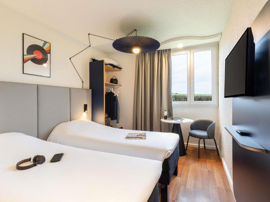 a hotel room with two beds and a window at ibis Chalons en Champagne in Châlons-en-Champagne