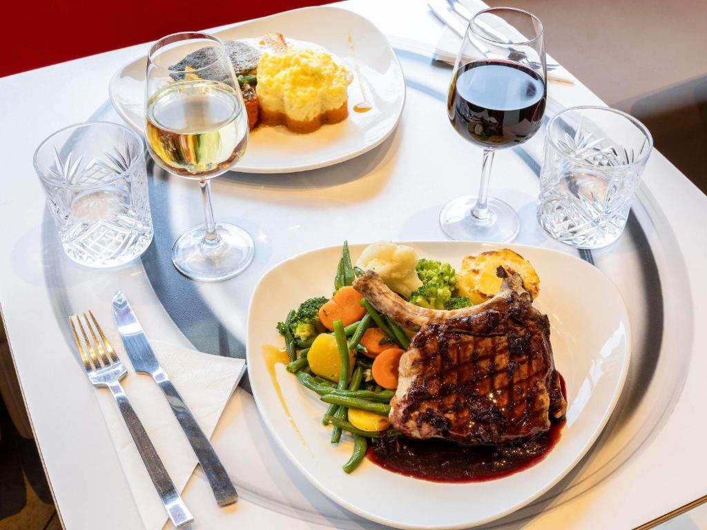 a table with two plates of food and glasses of wine at ibis Chalons en Champagne in Châlons-en-Champagne