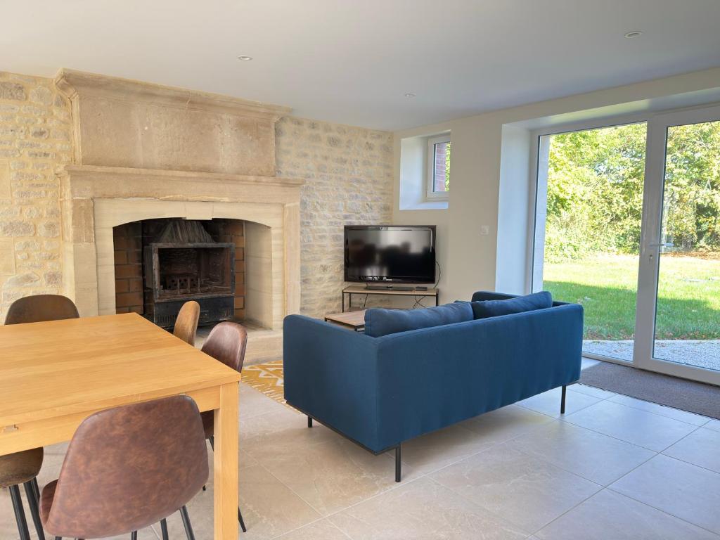 a living room with a blue couch and a fireplace at Le Mesnil in Bayeux