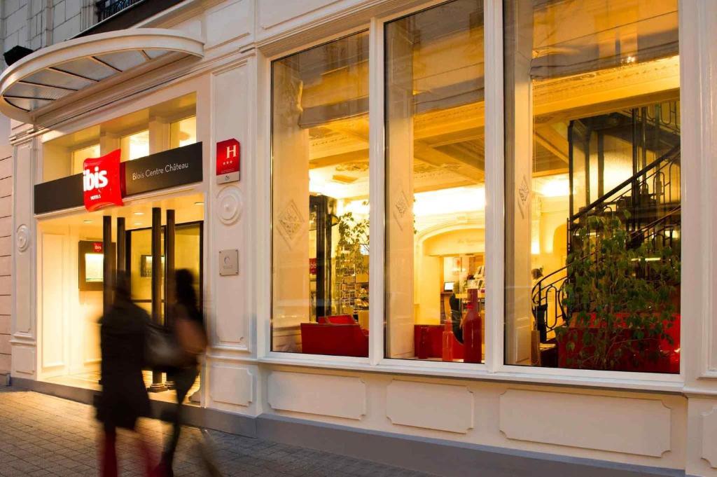 una persona che cammina davanti alla finestra di un negozio di ibis Blois Centre Château a Blois