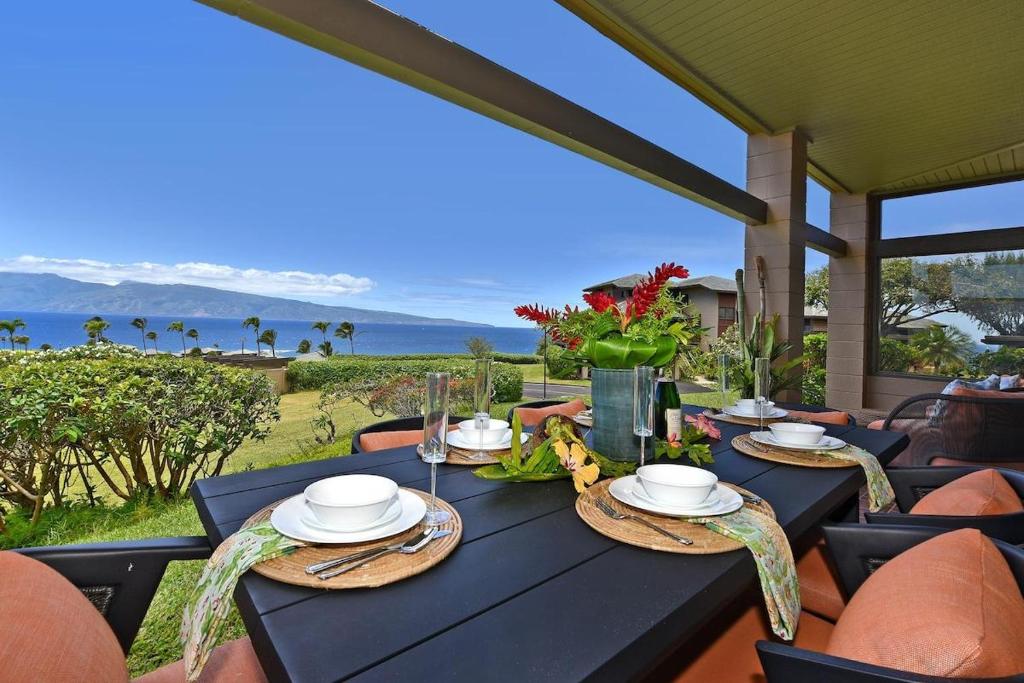 Una mesa negra con un jarrón de flores. en Kapalua Ridge Villas 2614 · KRV 2614 Remodeled Villa w Ocean Vie, en Kahana