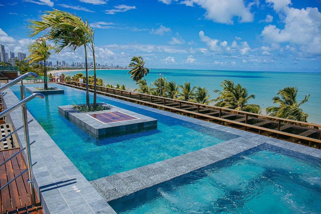 a swimming pool with the ocean in the background at Beira-mar do Cabo Branco com varanda UN113 in Penha