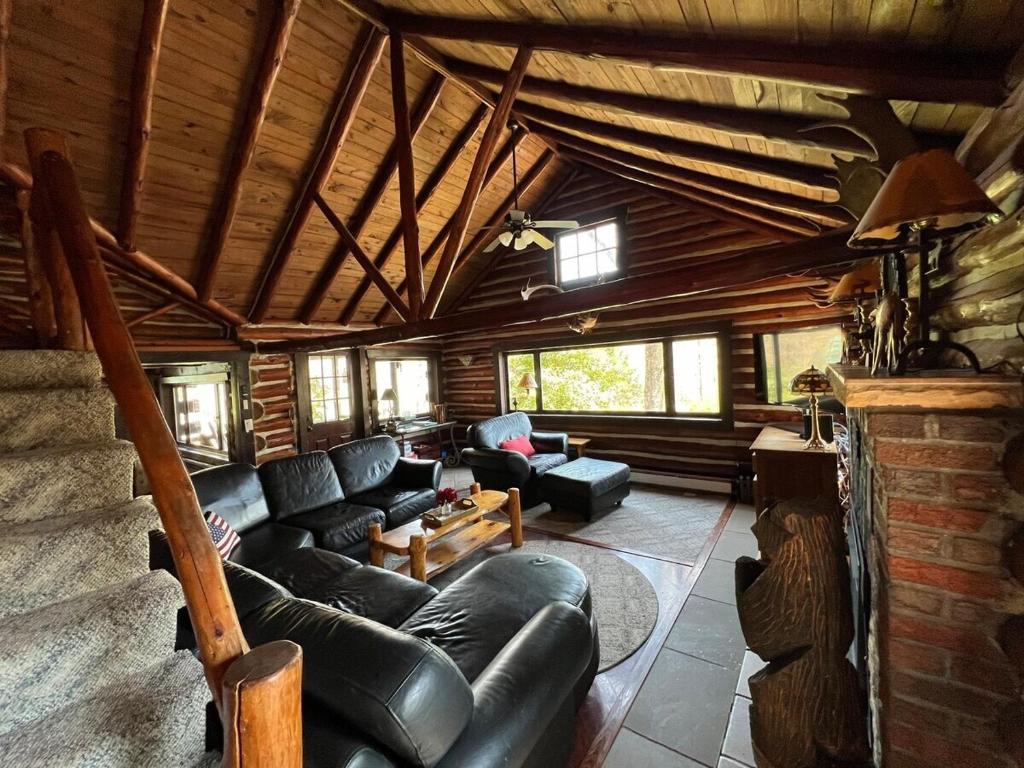 una sala de estar con muebles de cuero en una cabaña de madera en Stony Creek Lodge, en Kahkhout Mountain