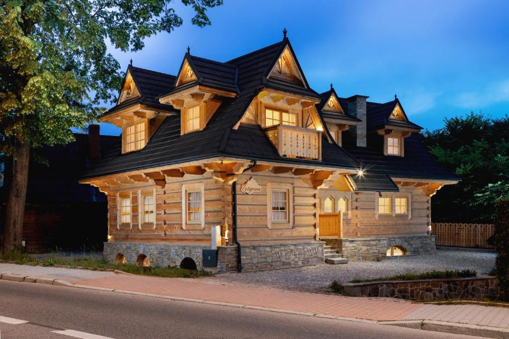 a large wooden house with a black roof at Zasypane Premium House & Sauna in Zakopane by Renters Prestige in Zakopane