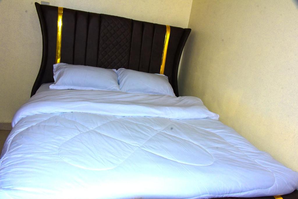 a bed with white sheets and a black headboard at Zariah Homes in Kakamega