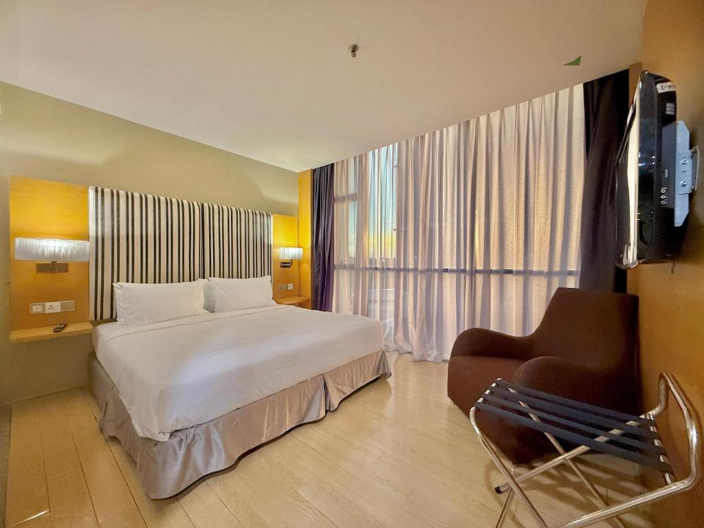 a hotel room with a bed and a chair and a television at NuEmpire Subang Suite - Empire Hotel in Subang Jaya