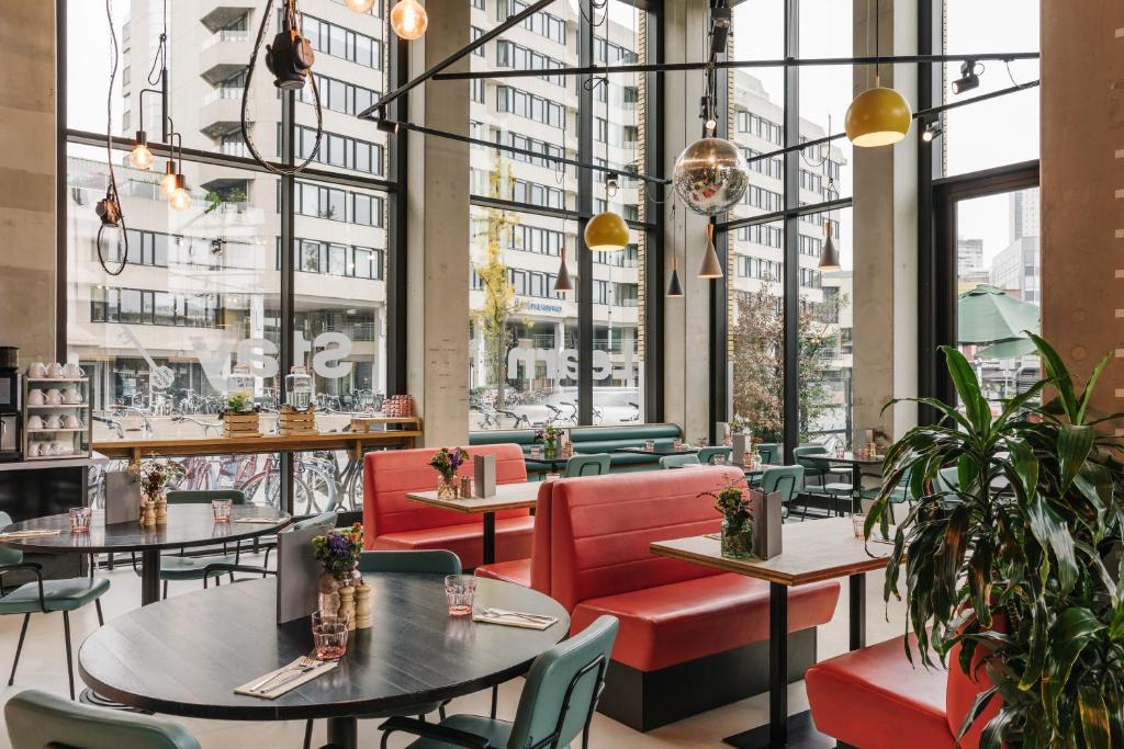 a restaurant with tables and chairs and large windows at The Social Hub Eindhoven Extended Stay in Eindhoven