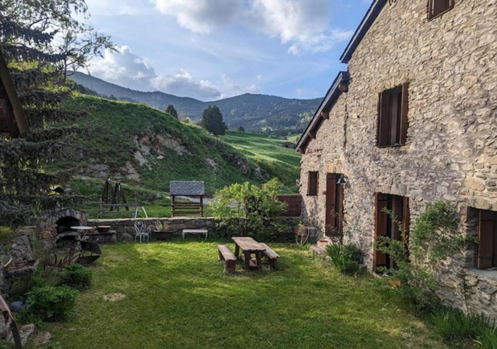 - un bâtiment en pierre avec une table de pique-nique dans une cour dans l'établissement Chalet familiale de montagne - Pyrénées-Orientales, à Puyvalador