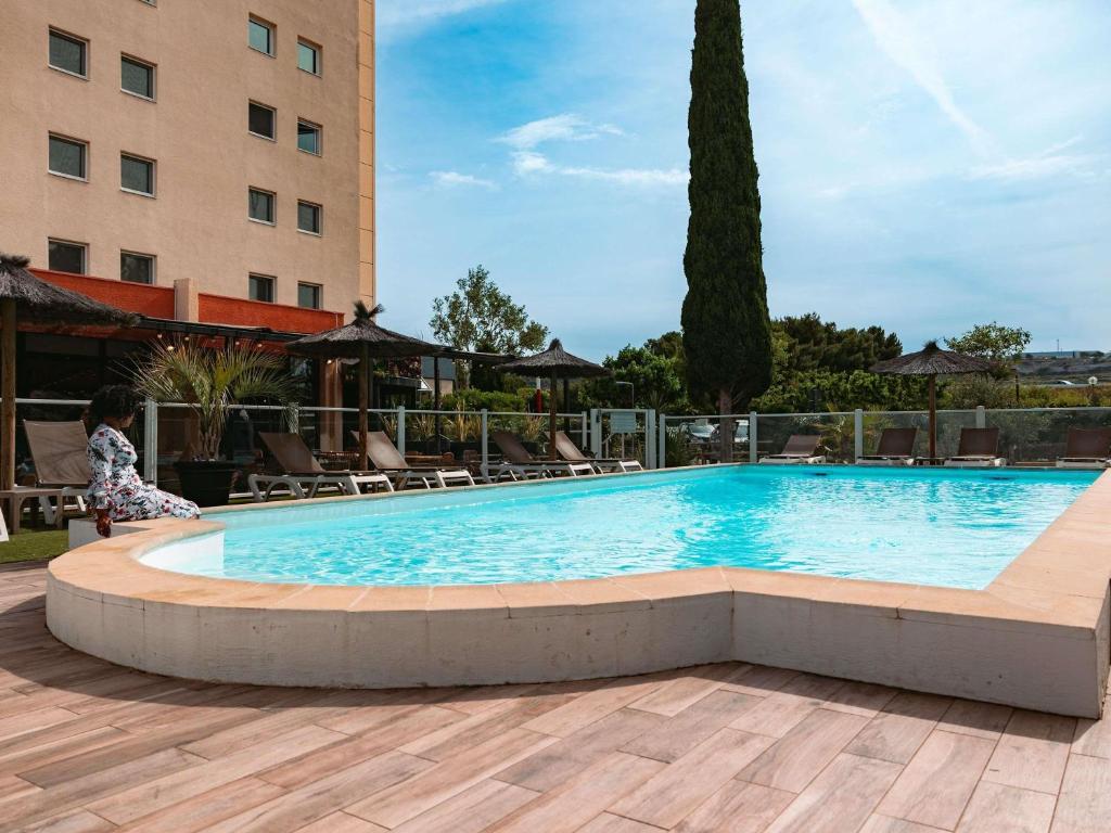 a large swimming pool in front of a hotel at ibis Marseille Provence Aéroport in Marignane