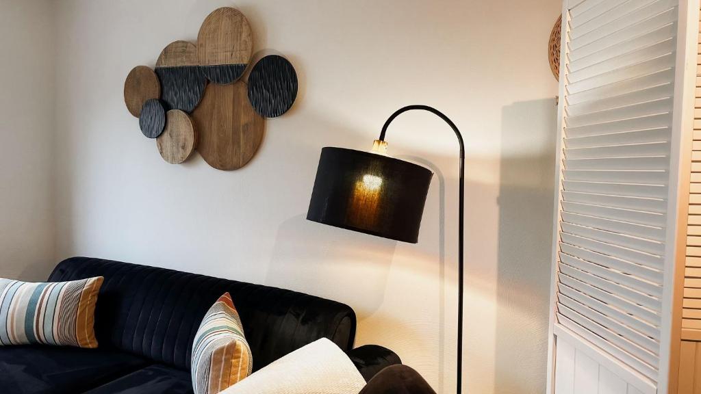 a living room with a black couch and a lamp at Gemütliches Ferienapartment Für jedes Budget in Horhausen