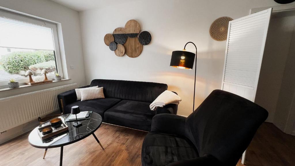 a living room with a black couch and a table at Gemütliches Ferienapartment Für jedes Budget in Horhausen