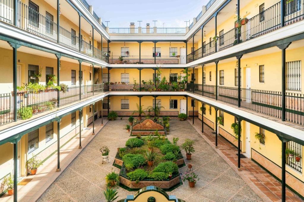 Un patio vacío de un edificio de apartamentos con plantas. en Alohamundi Rocío, en Sevilla