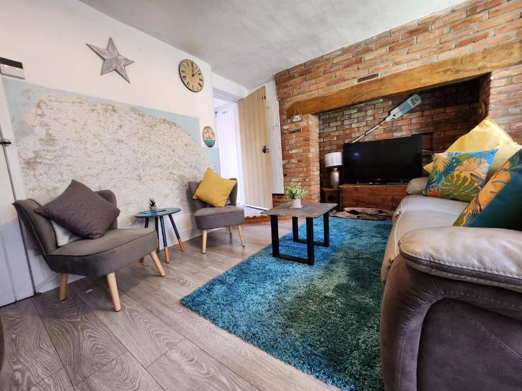 a living room with a couch and chairs and a tv at AnchorageWells Entire Cottage in Wells next the Sea